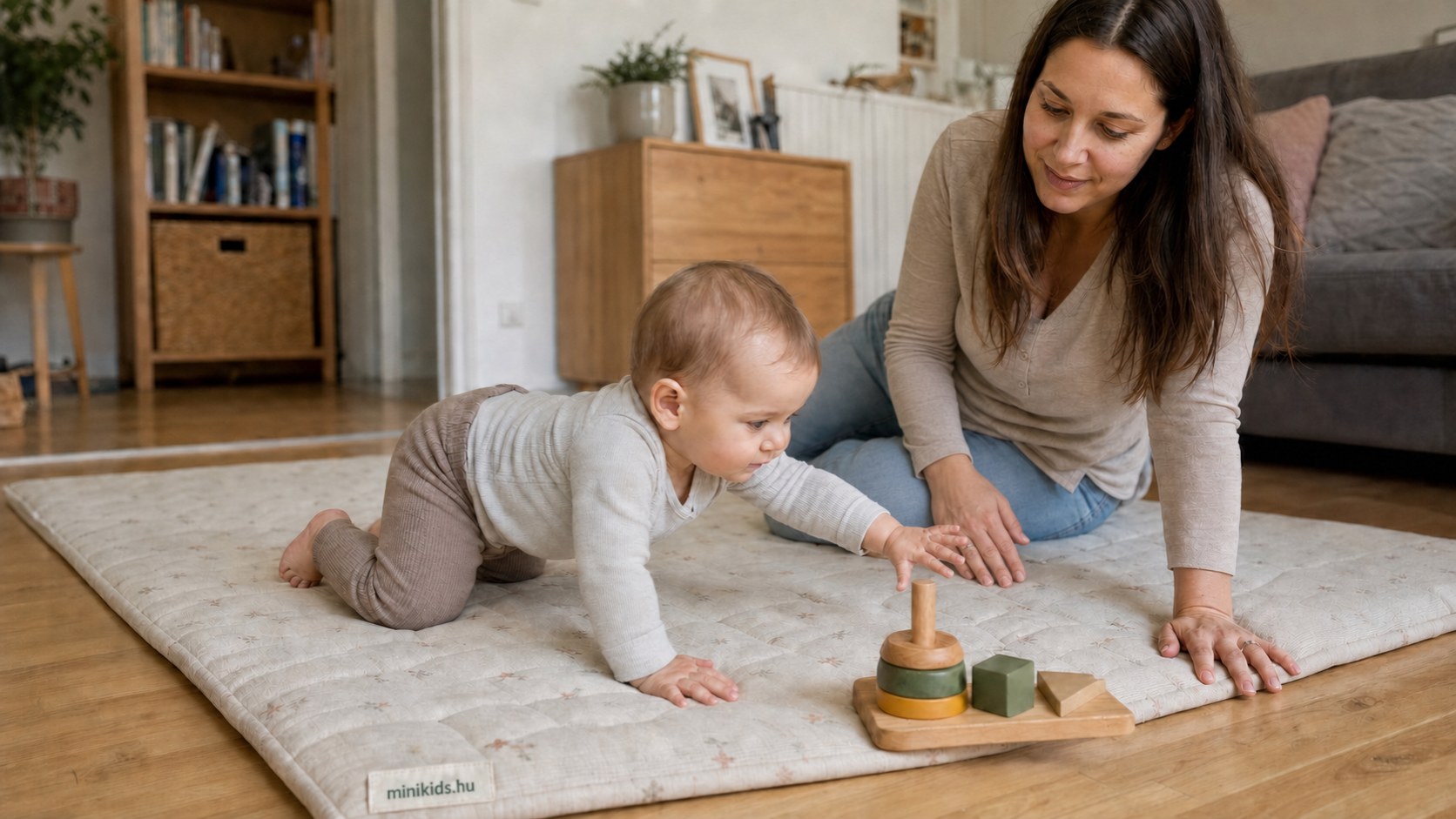 Baba puha játszószőnyegen mászik egy fajáték felé, az édesanyja mellette ül a padlón